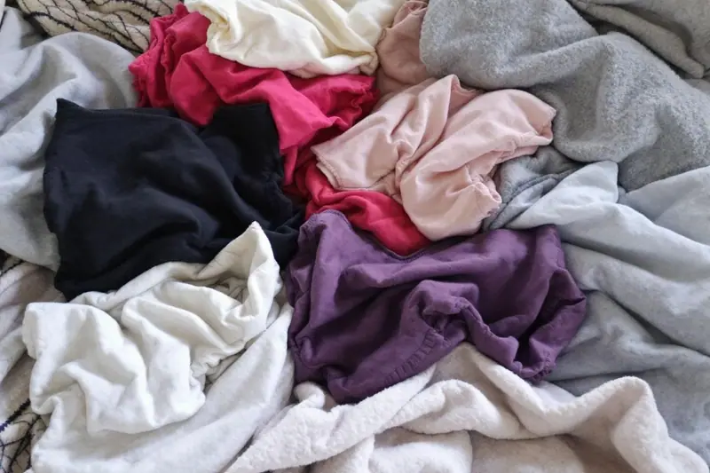 Culotte menstruelle noire en coton posée à plat sur une serviette claire, avec une lessive douce à côté