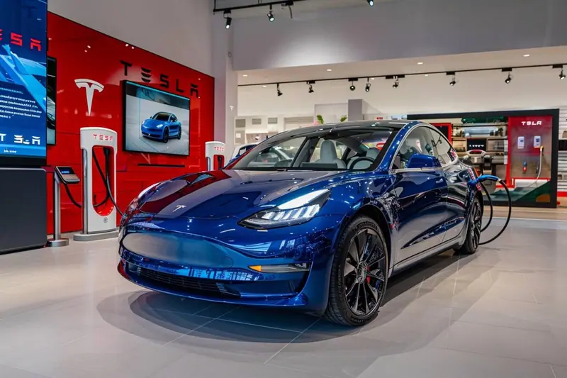 Une Tesla Model 3 blanche stationnée devant une maison, avec un siège auto et une poussette prêts à être rangés
